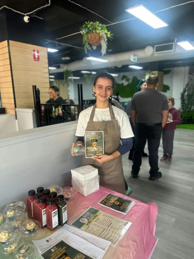A Köfi Köfi team member at a party catering stand with cold-pressed juices and menus
