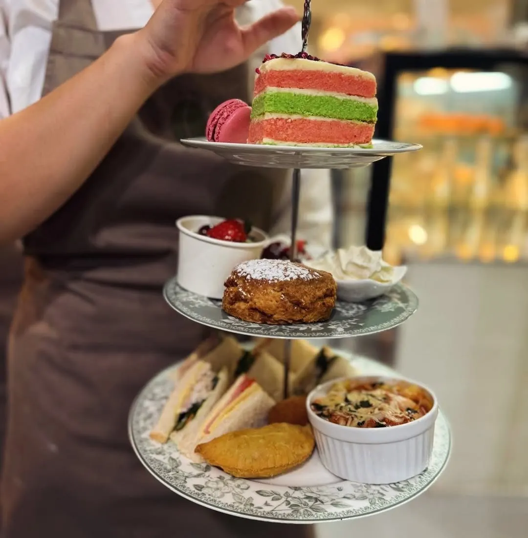 Close view of ribbon sandwiches, a savoury pastry and quiche on the bottom tier of a high tea stand