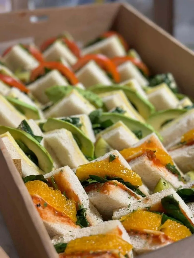 A box of ribbon sandwiches filled with avocado, orange, kiwi, tomato and herbs