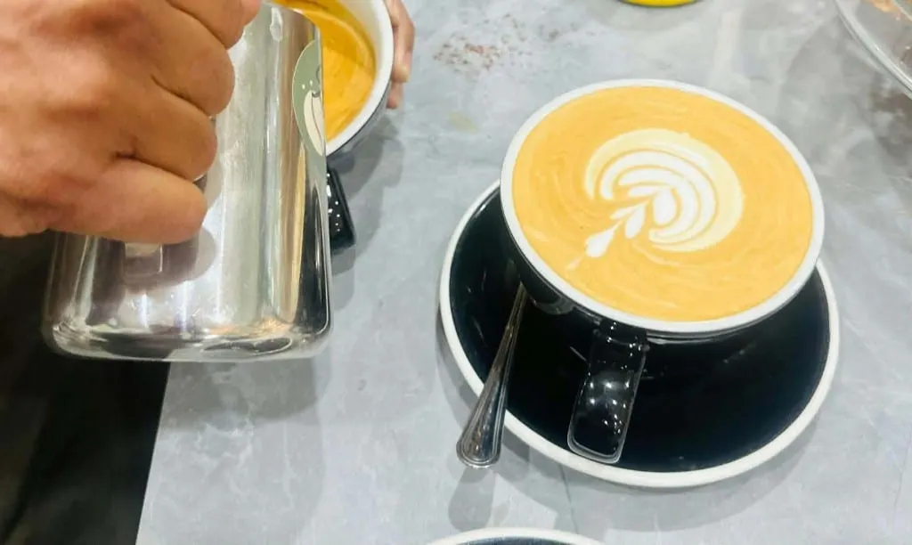 Latte art being poured into a cup at Köfi Köfi