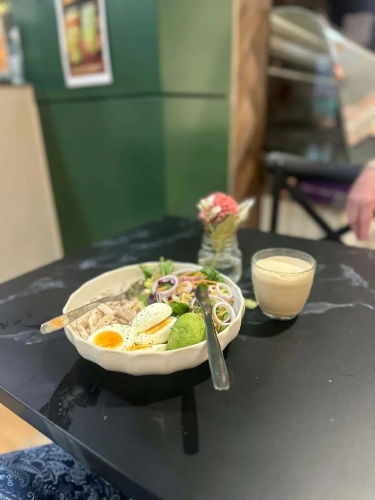 A cafe salad with chicken, avocado, boiled egg, red onion and greens
